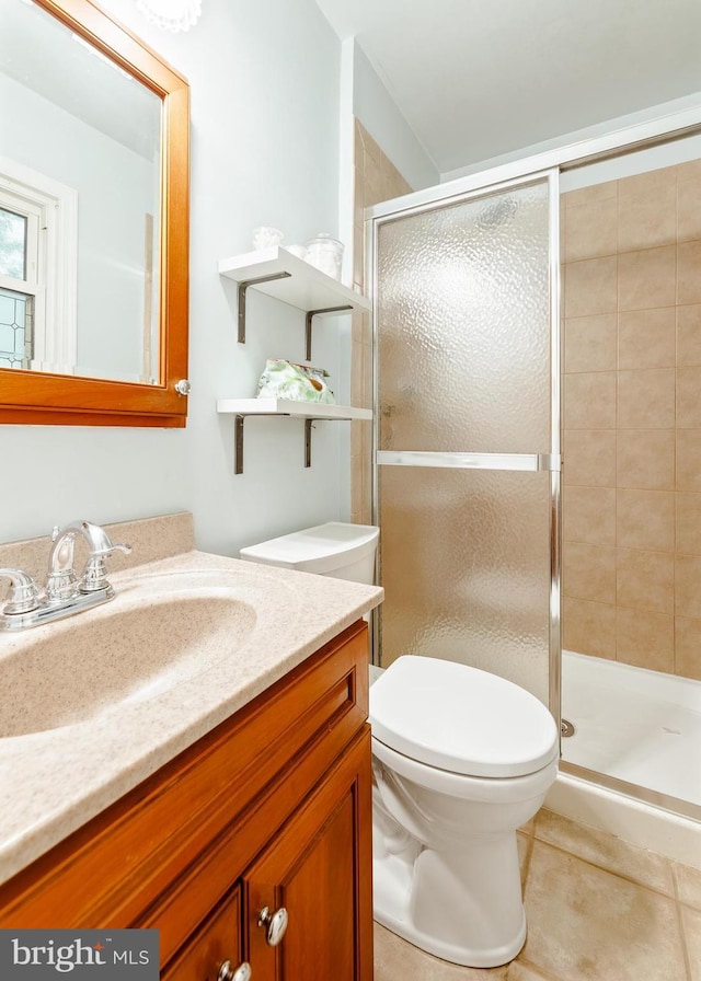 bathroom with a shower stall, toilet, vanity, and tile patterned flooring