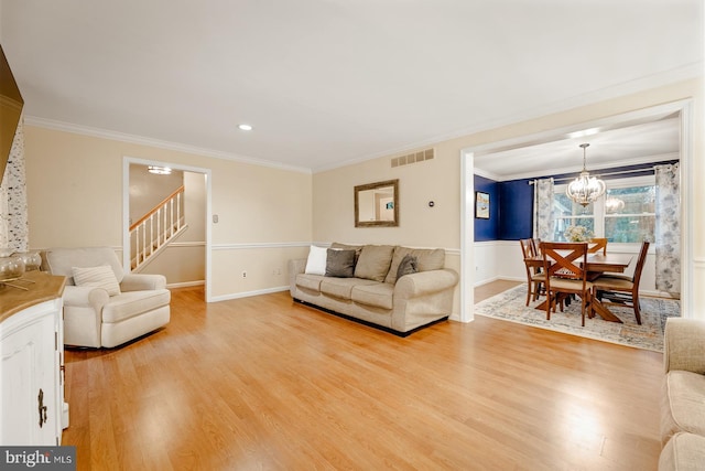 living area featuring crown molding, light wood finished floors, a chandelier, stairway, and baseboards