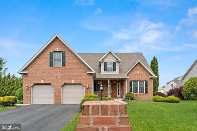 traditional home with a front yard, brick siding, a garage, and aphalt driveway