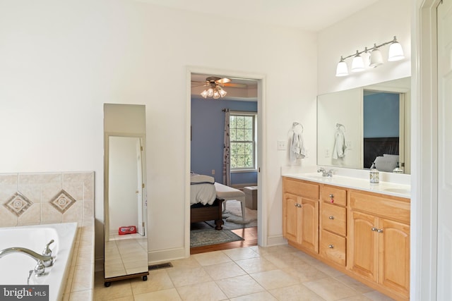 bathroom with double vanity, connected bathroom, a ceiling fan, tile patterned flooring, and tiled tub