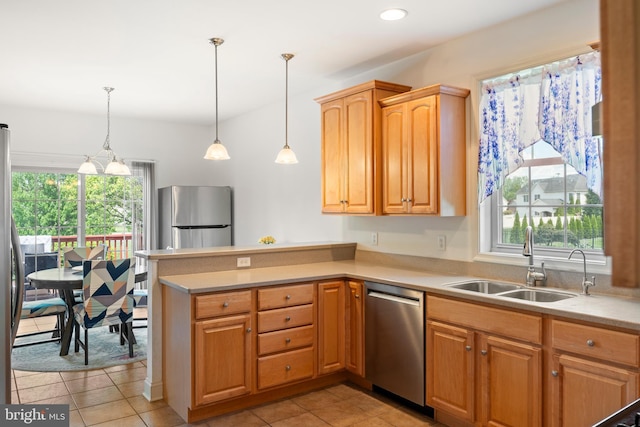 kitchen with a peninsula, stainless steel appliances, a healthy amount of sunlight, and a sink
