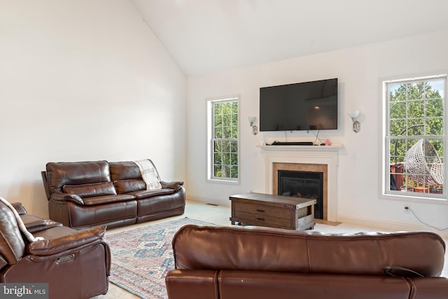 carpeted living area featuring baseboards, a glass covered fireplace, and high vaulted ceiling