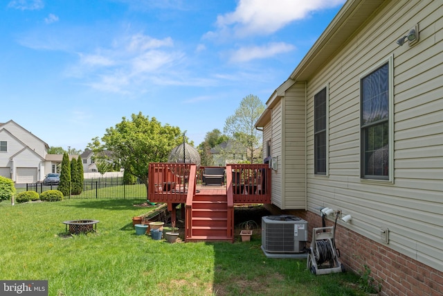 view of yard with central air condition unit, an outdoor fire pit, a deck, and fence