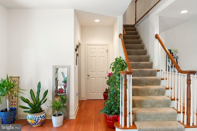 stairs with baseboards, recessed lighting, and wood-type flooring