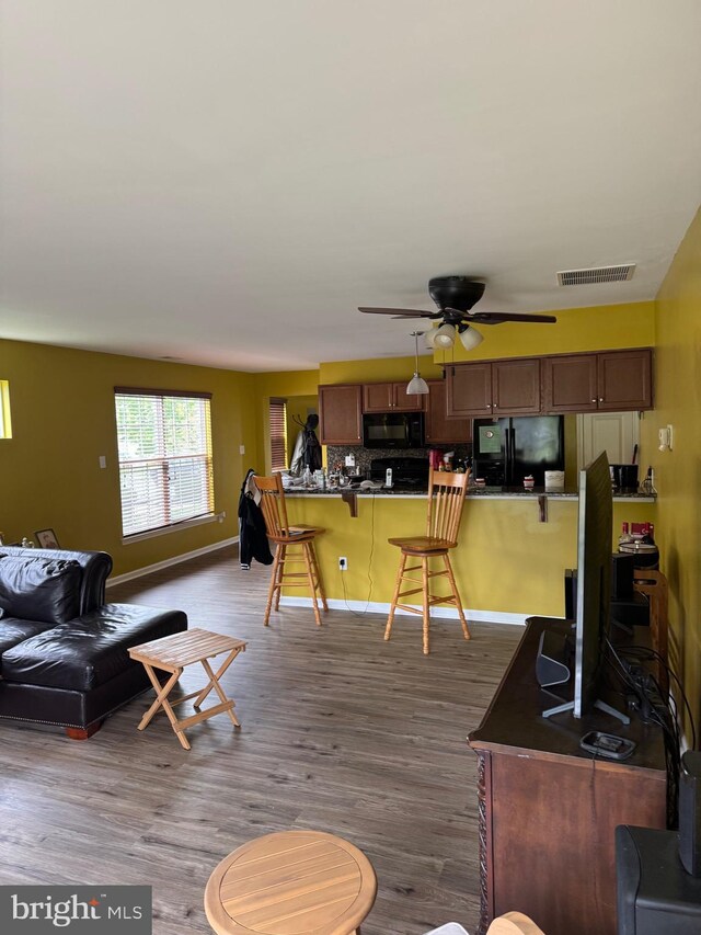 living area with baseboards, a ceiling fan, visible vents, and dark wood finished floors