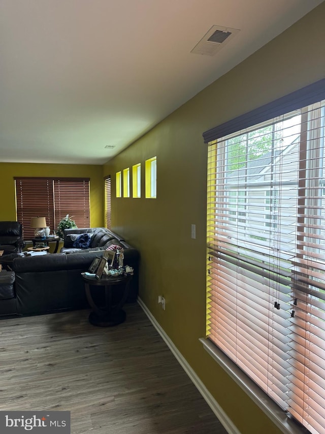 living room featuring a wealth of natural light, visible vents, wood finished floors, and baseboards