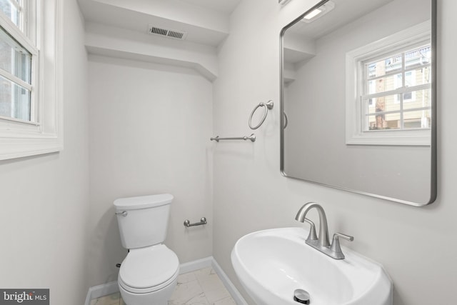 722 S Clinton St, Baltimore, MD 21224 - half bathroom featuring marble look tiles, baseboards, toilet, and a sink