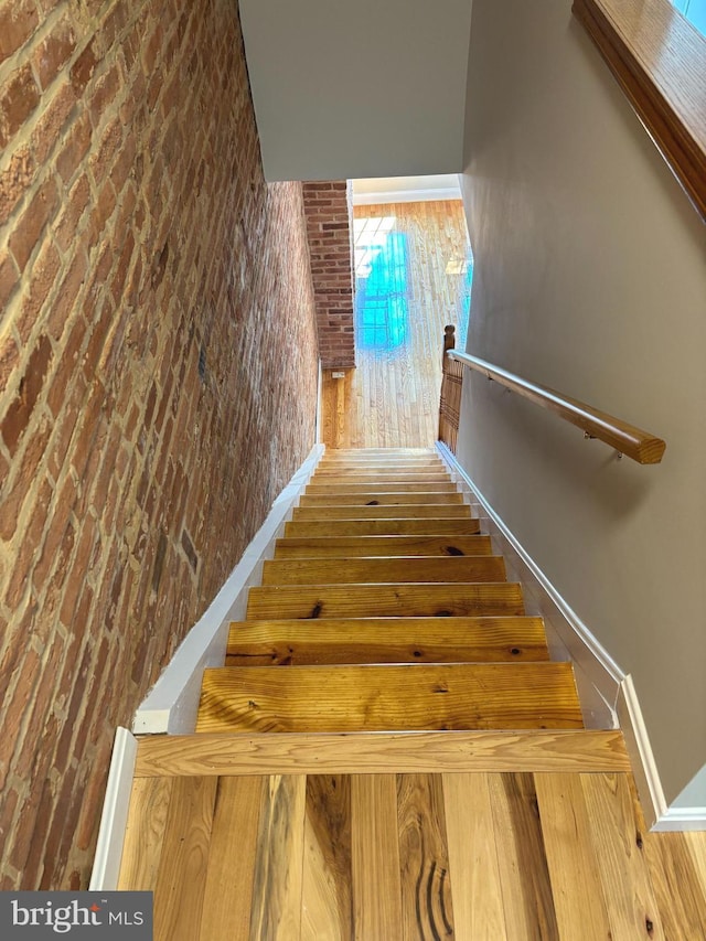 722 S Clinton St, Baltimore, MD 21224 - stairs with hardwood / wood-style floors, brick wall, and baseboards