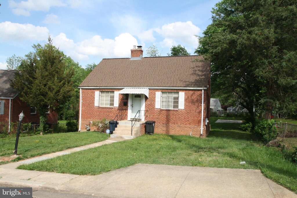 5205 58th Ave, Hyattsville, MD 20781 - cape cod house with roof with shingles, a chimney, brick siding, and a front yard