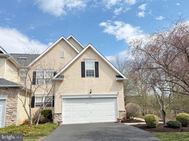 view of front of home with stone siding, stucco siding, and aphalt driveway