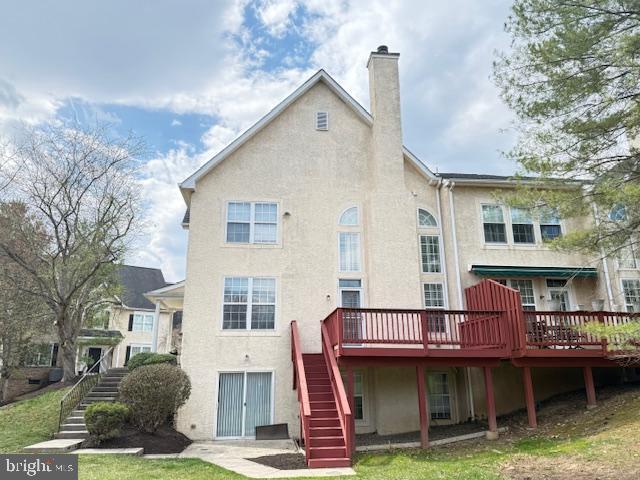 back of property featuring a chimney, stairway, and stucco siding