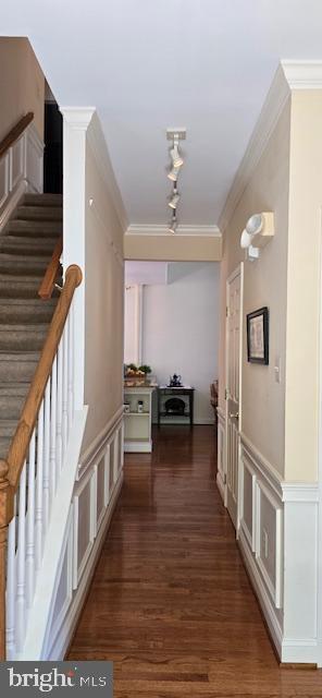 hallway with wood finished floors, ornamental molding, and stairs