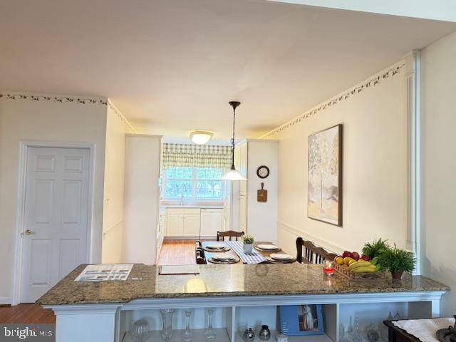 kitchen featuring dark stone counters, wood finished floors, and decorative light fixtures