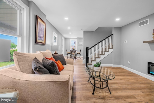 living area with stairs, wood finished floors, visible vents, recessed lighting, and baseboards