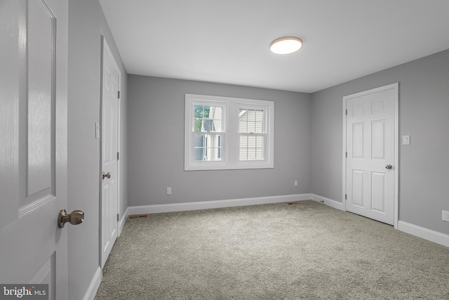 spare room featuring carpet flooring and baseboards