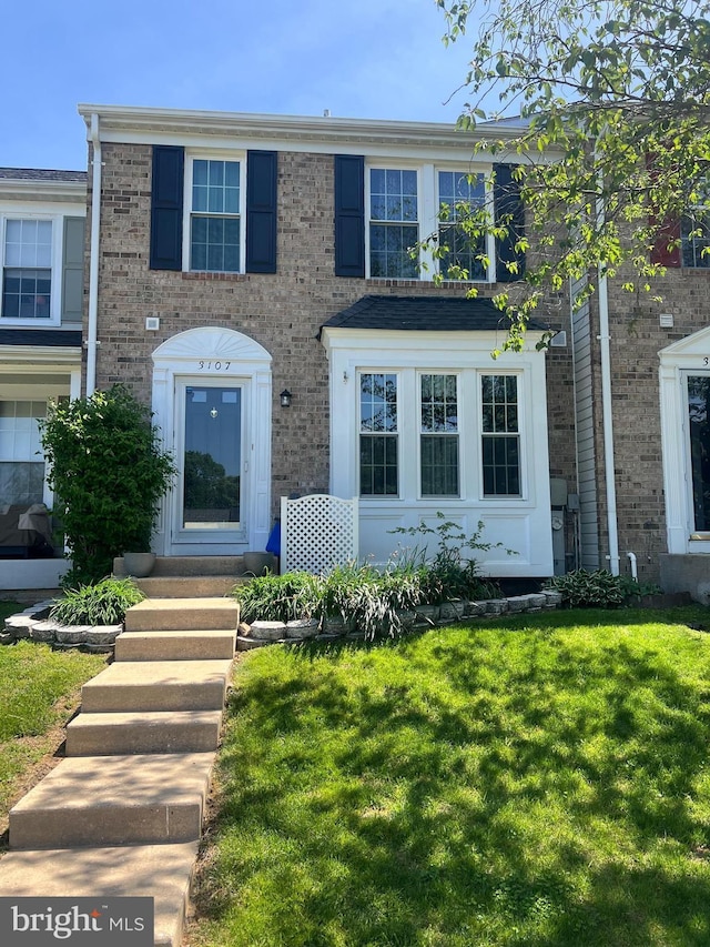 view of front of house featuring entry steps, brick siding, and a front yard