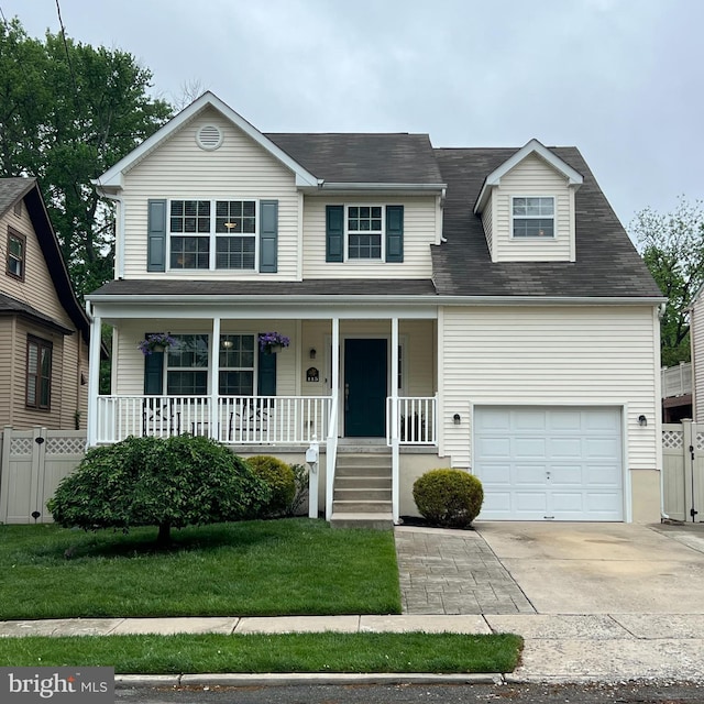 traditional-style home with covered porch, fence, concrete driveway, and a front yard