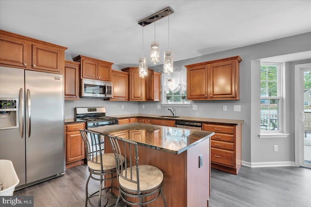 kitchen featuring brown cabinetry, stainless steel appliances, wood finished floors, and a sink