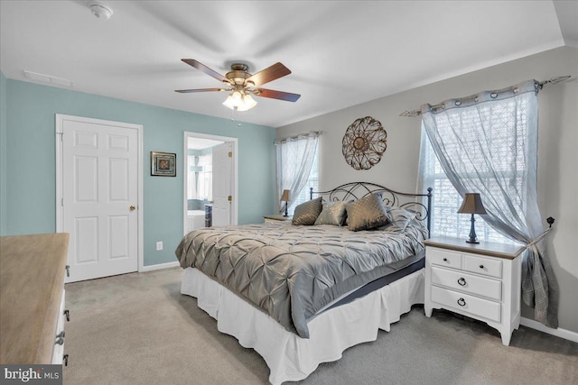 carpeted bedroom with connected bathroom, visible vents, baseboards, and a ceiling fan