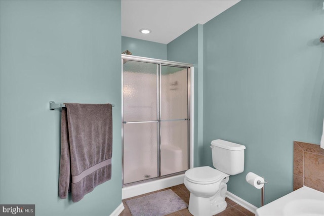 bathroom with a shower stall, baseboards, tile patterned floors, and toilet