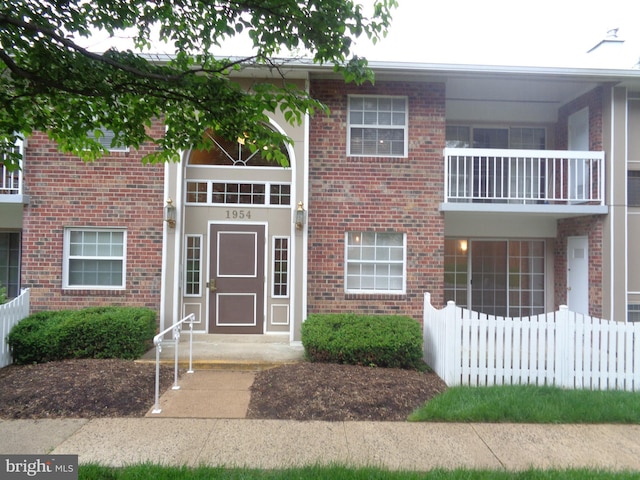 view of property featuring brick siding and fence