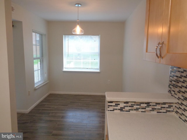 unfurnished dining area with baseboards and dark wood-style floors