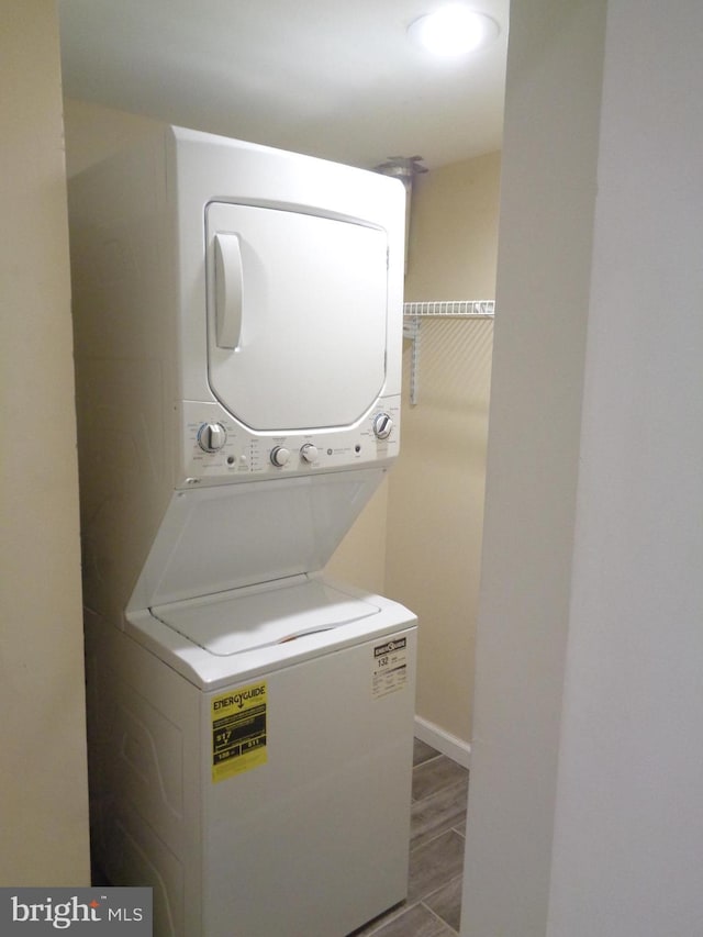 laundry room featuring stacked washer / dryer, laundry area, and wood finished floors