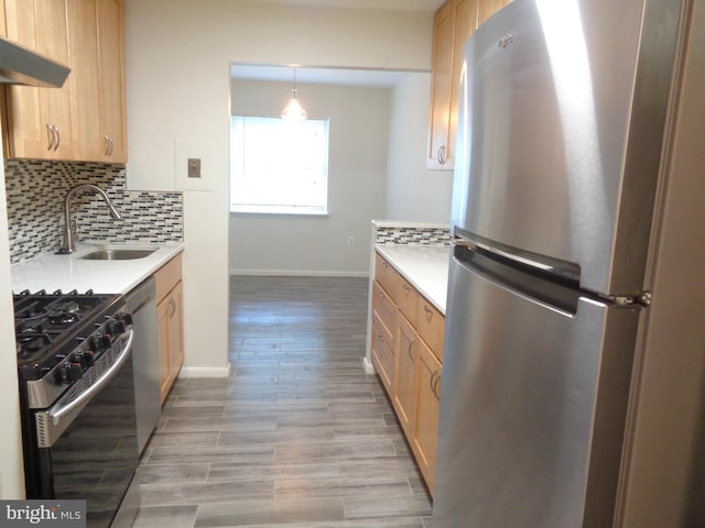 kitchen with light brown cabinetry, a sink, decorative backsplash, light countertops, and appliances with stainless steel finishes