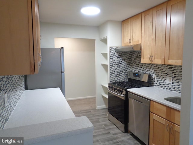 kitchen featuring under cabinet range hood, light countertops, stainless steel appliances, and tasteful backsplash
