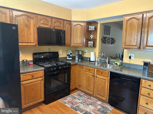 937 Dunloring Ct, Upper Marlboro, MD 20774 - kitchen with black appliances, a sink, light wood-style flooring, dark countertops, and brown cabinetry