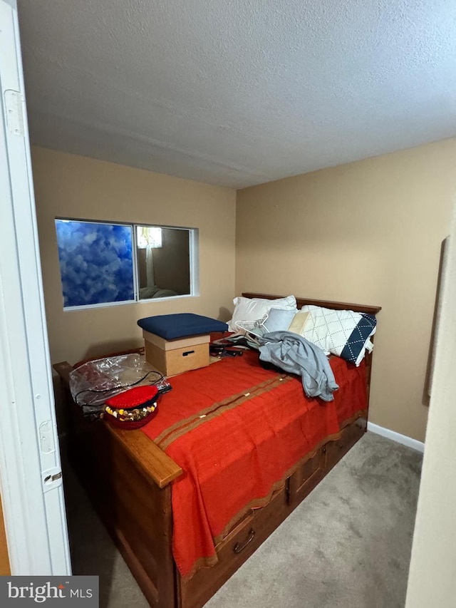 carpeted bedroom with a textured ceiling and baseboards
