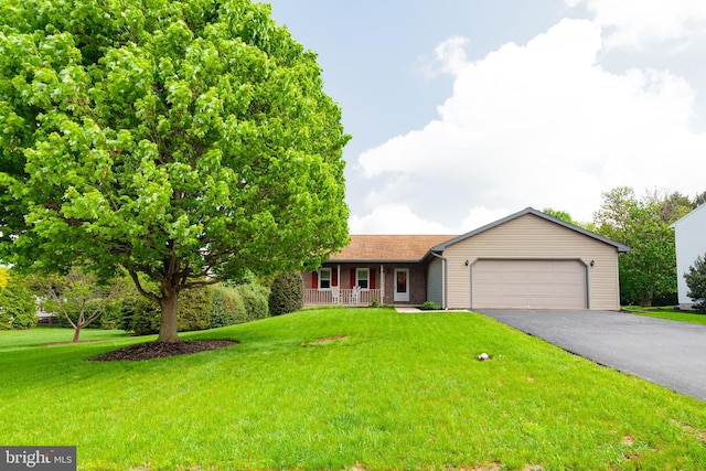 ranch-style home featuring a garage, covered porch, asphalt driveway, and a front yard