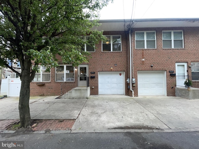 multi unit property featuring brick siding, driveway, and a garage