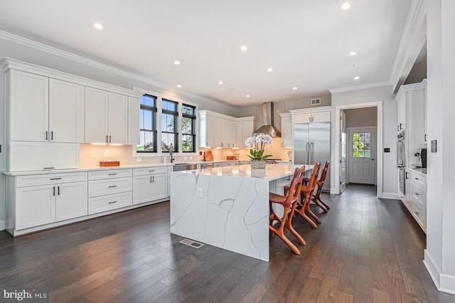 3015 Friends Rd, Annapolis, MD 21401 - kitchen featuring wall chimney range hood, a center island, appliances with stainless steel finishes, ornamental molding, and white cabinetry