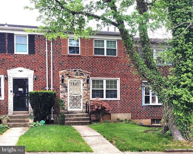 view of property with a front lawn and brick siding