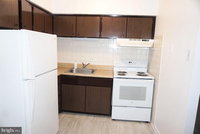 kitchen featuring white appliances, a sink, under cabinet range hood, tasteful backsplash, and light countertops