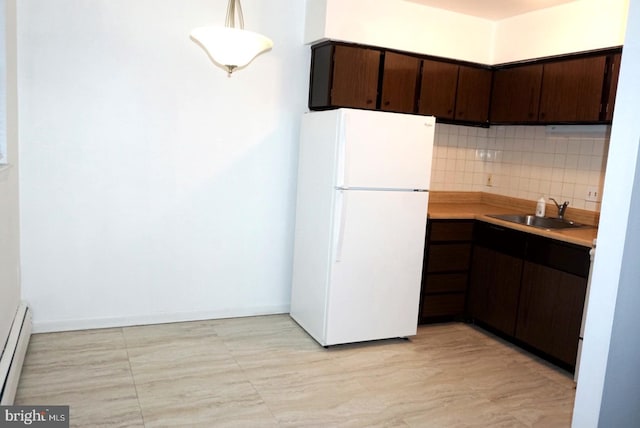 kitchen with freestanding refrigerator, a sink, dark brown cabinetry, backsplash, and a baseboard radiator