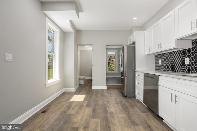kitchen featuring dark wood-style flooring, decorative backsplash, light countertops, white cabinets, and appliances with stainless steel finishes
