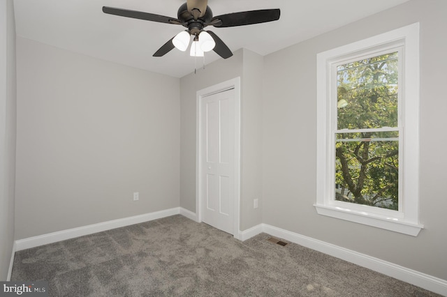 unfurnished bedroom with a closet, visible vents, ceiling fan, carpet floors, and baseboards
