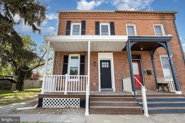 view of property featuring a porch and brick siding