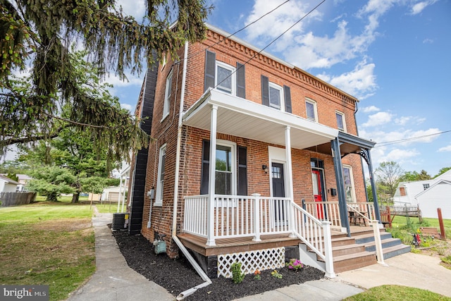 view of front of home with covered porch, brick siding, and a front lawn