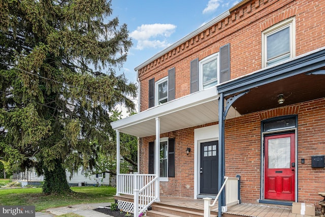 view of property with a porch and brick siding