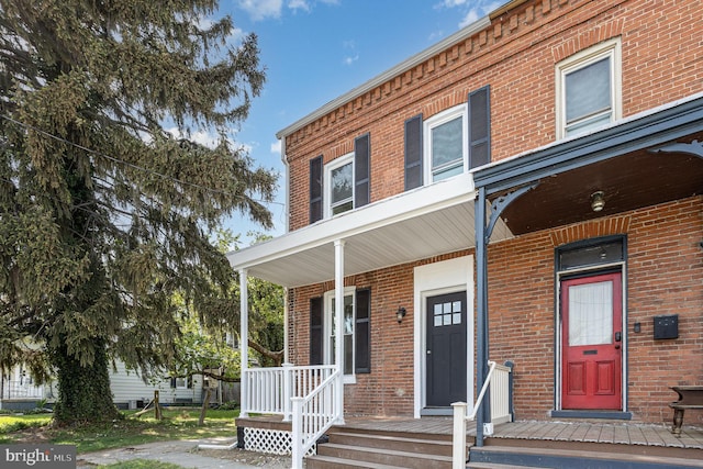 view of property featuring covered porch and brick siding