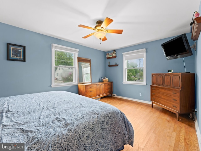 bedroom with light wood finished floors, baseboards, and a ceiling fan