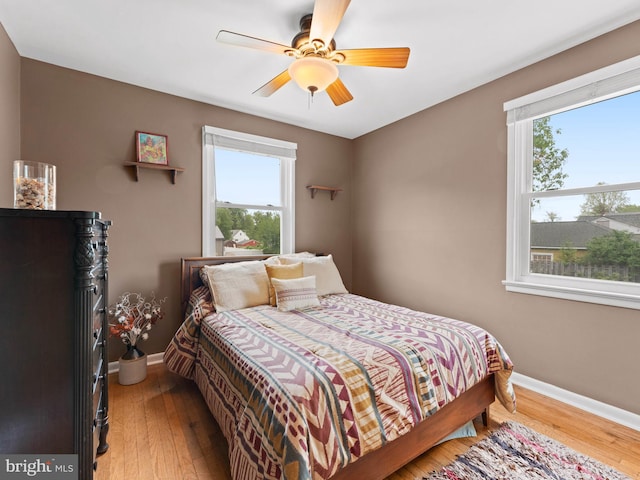 bedroom featuring light wood finished floors, multiple windows, and baseboards