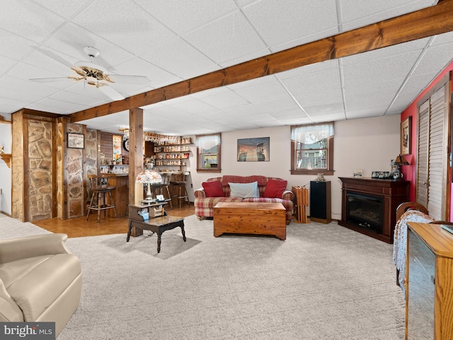 living room featuring a paneled ceiling, a fireplace, and carpet floors