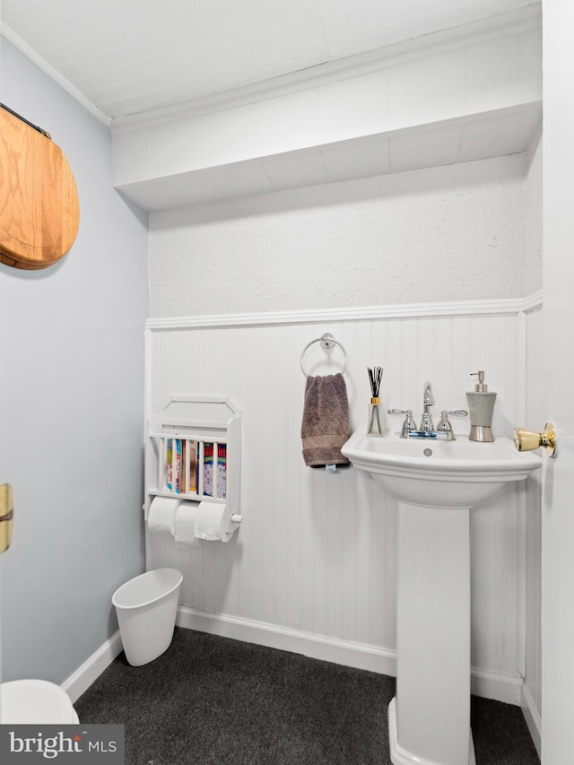 bathroom with wainscoting, ornamental molding, and toilet