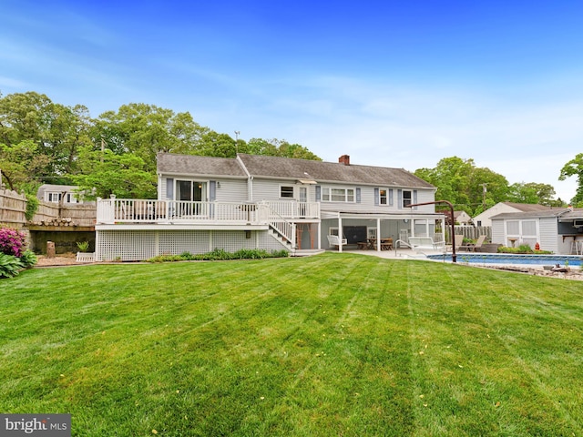back of house featuring a lawn, a wooden deck, an outdoor pool, and fence