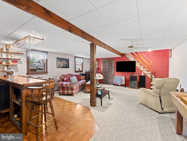 living room with stairs, a drop ceiling, and a bar