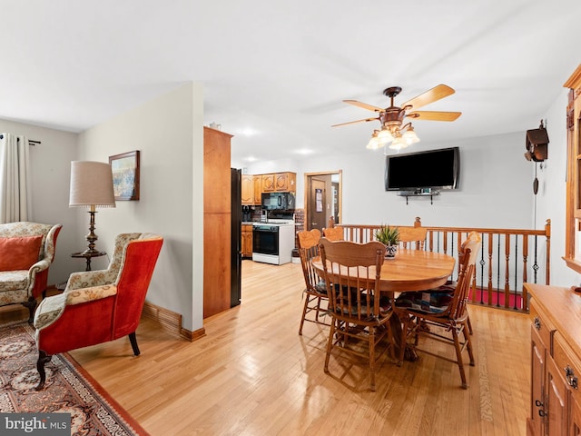 dining area featuring light wood finished floors, baseboards, and ceiling fan